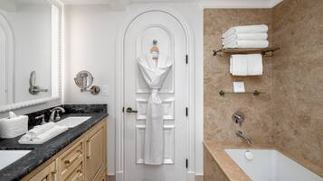 A modern bathroom with a marble sink, a bathtub, and a towel rack.