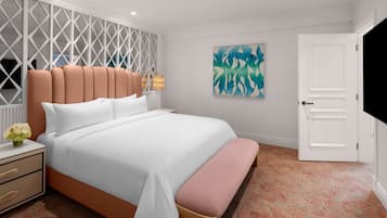 A modern bedroom with a large bed, a nightstand, a bench, a wall-mounted TV, and a door.