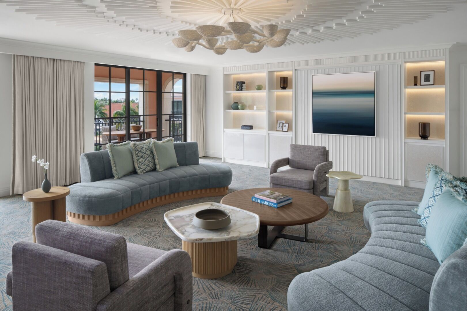 Una sala de estar moderna con un sofá modular, sillones, una mesa de centro y estanterías empotradas con objetos decorativos.