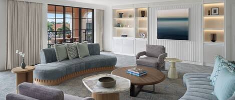 Una sala de estar moderna con un sofá modular, sillones, una mesa de centro y estanterías empotradas con objetos decorativos.