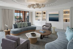 A modern living room with a sectional sofa, armchairs, a coffee table, and built-in shelving with decorative items. - Palm House Hotel Palm Beach (Palm Beach)