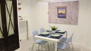 Un comedor con una mesa blanca para cuatro, sillas azul claro y un cuadro en la pared.