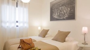 A hotel room with two beds, a large painting on the wall, and a round table with a lamp. - Duque 3 · Apartment with Terrace · 2 Bedrooms · 2 Bathrooms (Córdoba)
