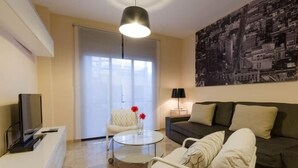 A modern living room with a sofa, a coffee table, a TV, and a painting on the wall. - Duque 3 · Apartment with Terrace · 2 Bedrooms · 2 Bathrooms (Córdoba)