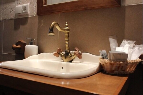 A bathroom sink with a brass faucet, a white soap dispenser, and a wicker basket with toiletries. - Casa del Río 2 · Studio Triple Standard without terrace · 1 Bed · 1 Bathroom (Córdoba)
