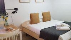 Une chambre d’hôtel bien rangée, avec un lit, une table de chevet et une chaise.