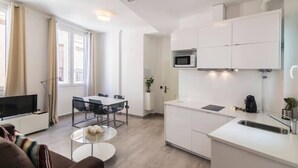 A modern kitchen with white cabinets, a microwave, and a sink. There is a dining area with a table and chairs. - Tendillas 5 · Apartment · 2 bedrooms · 1 sofa bed · 2 bathrooms (Córdoba)