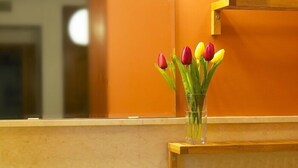 Une salle de bain avec une étagère en bois sur laquelle est posé un vase en verre contenant des tulipes.