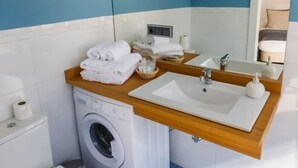 A compact bathroom with a washing machine, a sink, and a toilet. - Tendillas · Studio with terrace · 1 bed · 1 bathroom (Córdoba)