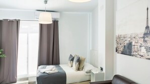 A modern hotel room with a bed, a desk, a chair, and a large window. - Tendillas · Studio with terrace · 1 bed · 1 bathroom (Córdoba)