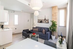A modern living room with a grey sofa, a coffee table, and a dining table. There is a potted plant and a painting of the Eiffel Tower on the wall. - Tendillas 7 · Apartment · 2 bedrooms · 1 sofa bed · 2 bathrooms (Córdoba)