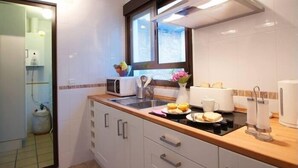 A modern kitchen with white cabinets, a wooden countertop, a window, and a sink. - Duque 1 · Apartment with Terrace · 2 Bedrooms · 2 Bathrooms (Córdoba)