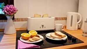 A breakfast setup with a toaster, a coffee maker, and a plate with bread, orange slices, and cookies. - Duque 1 · Apartment with Terrace · 2 Bedrooms · 2 Bathrooms (Córdoba)