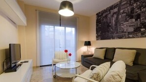 A modern living room with a sofa, armchair, coffee table, and a television on a stand. - Duque 1 · Apartment with Terrace · 2 Bedrooms · 2 Bathrooms (Córdoba)