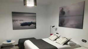 A modern bedroom with a bed, bedside tables, a small round table with a bowl, and two wall-mounted paintings. - Casa del Río 4 · Standard Studio without terrace · 1 Bed · 1 Bathroom (Córdoba)