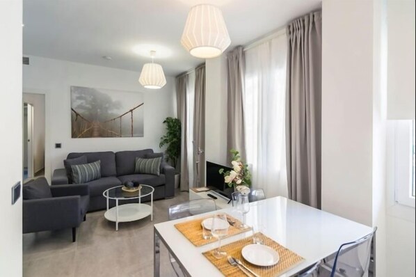 Una sala de estar moderna con sofá, mesa de centro y mesa de comedor preparada para dos comensales.