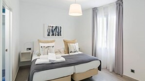 A modern bedroom with a double bed, a bedside table, a lamp, and a painting on the wall.
