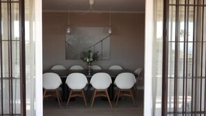 A dining area with a long table, six chairs, and hanging pendant lights.