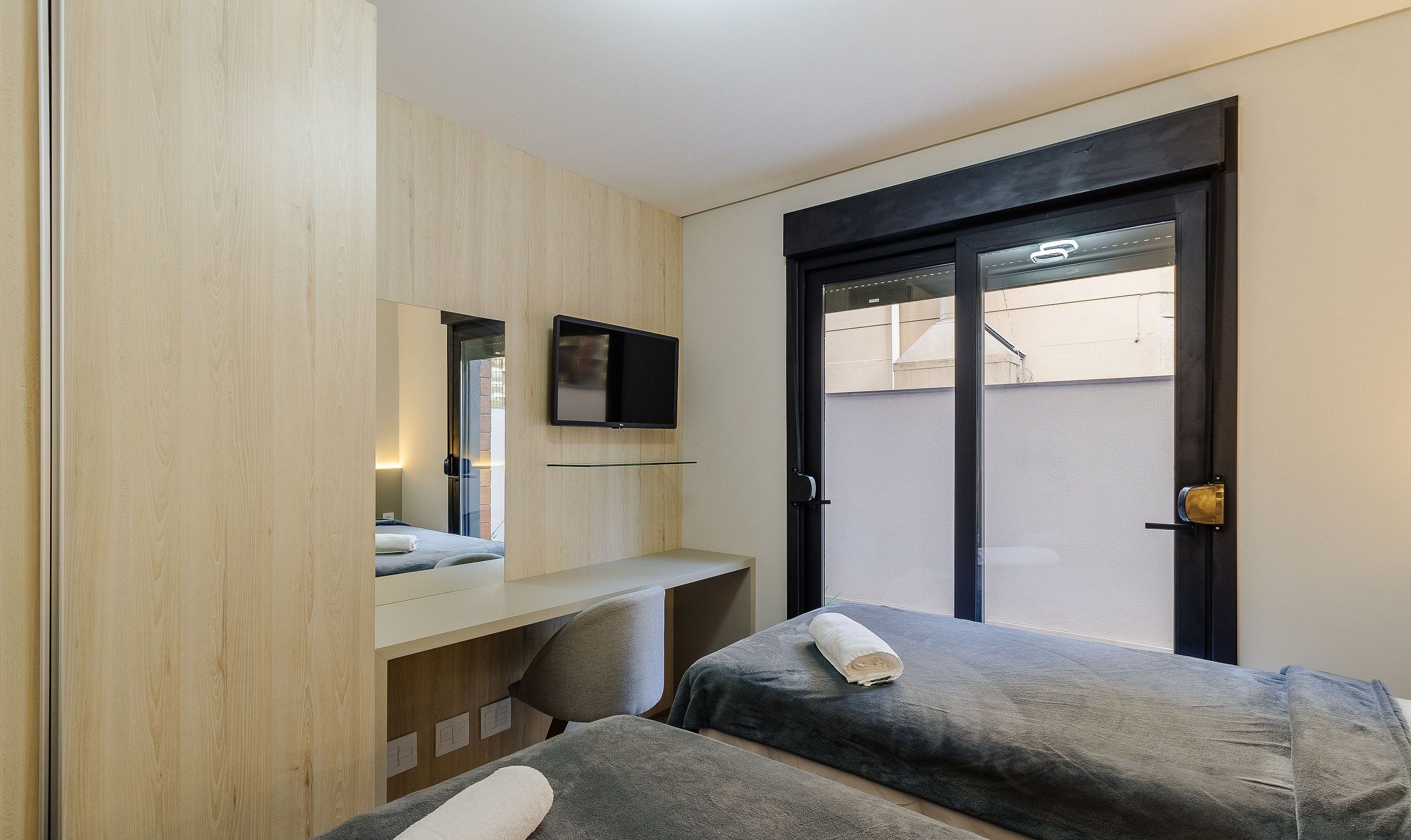 A hotel room with a bed, a desk, a television, and a window with a view.