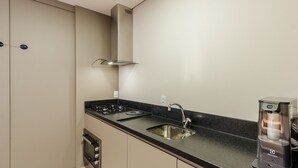 A modern kitchen with a stainless steel range hood, a sink, and a water dispenser. - DLH Aptos no Coração de Gramado (Gramado)