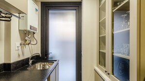 A compact bathroom with a sink, a mirror, and a frosted glass door. - DLH Aptos no Coração de Gramado  (Gramado)