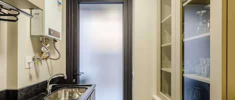 A compact bathroom with a sink, a mirror, and a frosted glass door.