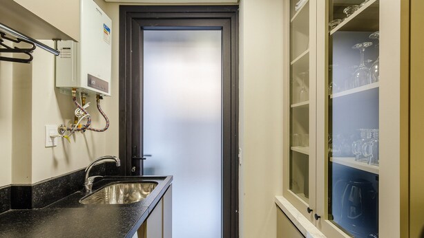 A compact bathroom with a sink, a mirror, and a frosted glass door. - DLH Aptos no Coração de Gramado (Gramado)