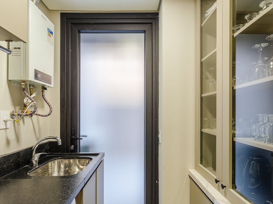 Ein kleines Badezimmer mit Waschbecken, Spiegel und Tür aus Milchglas.