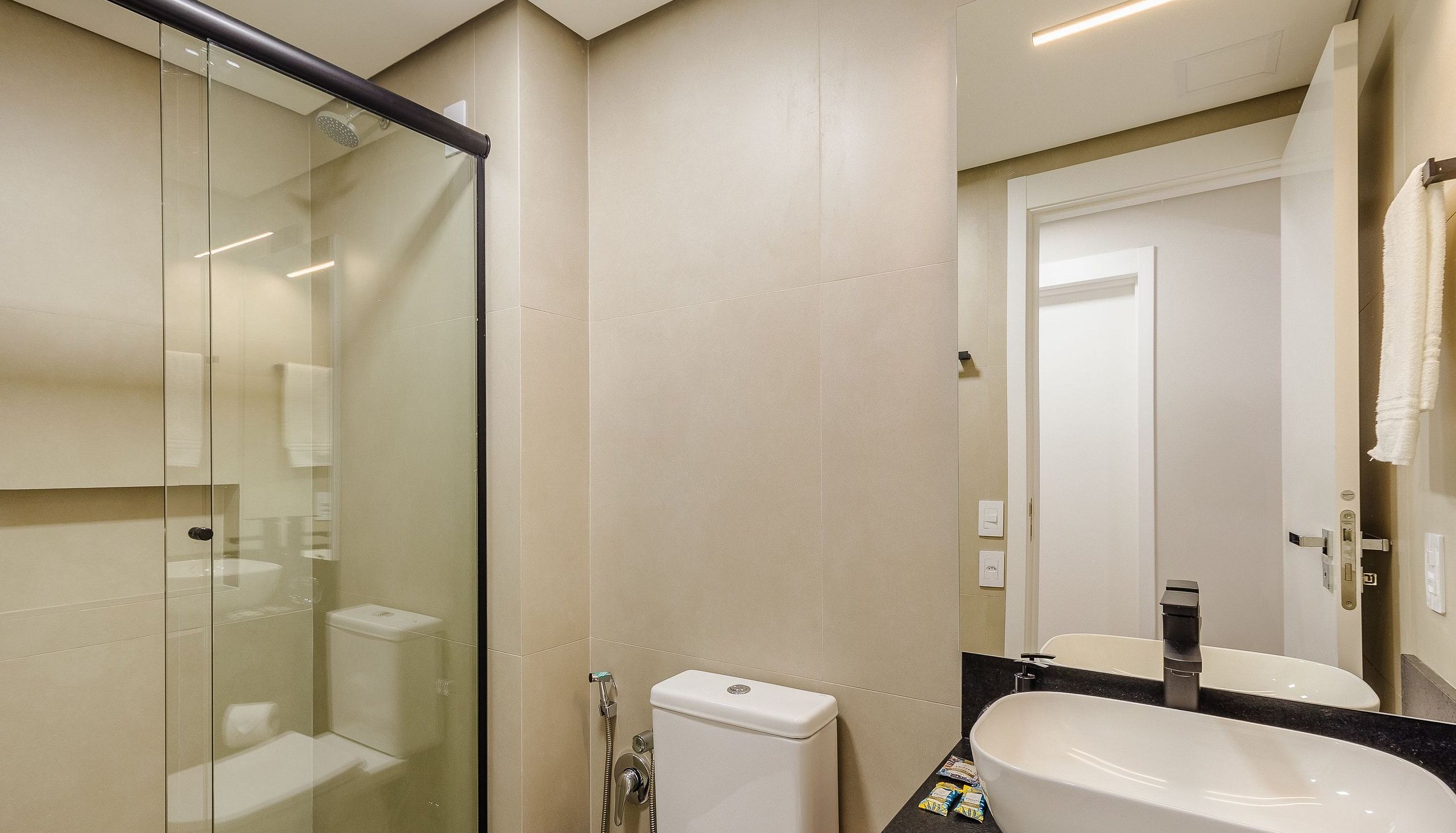Un baño moderno con cabina de ducha de vidrio, un inodoro y un lavabo con espejo.