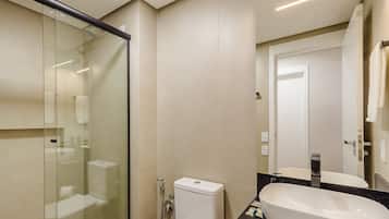 Un baño moderno con cabina de ducha de vidrio, un inodoro y un lavabo con espejo.