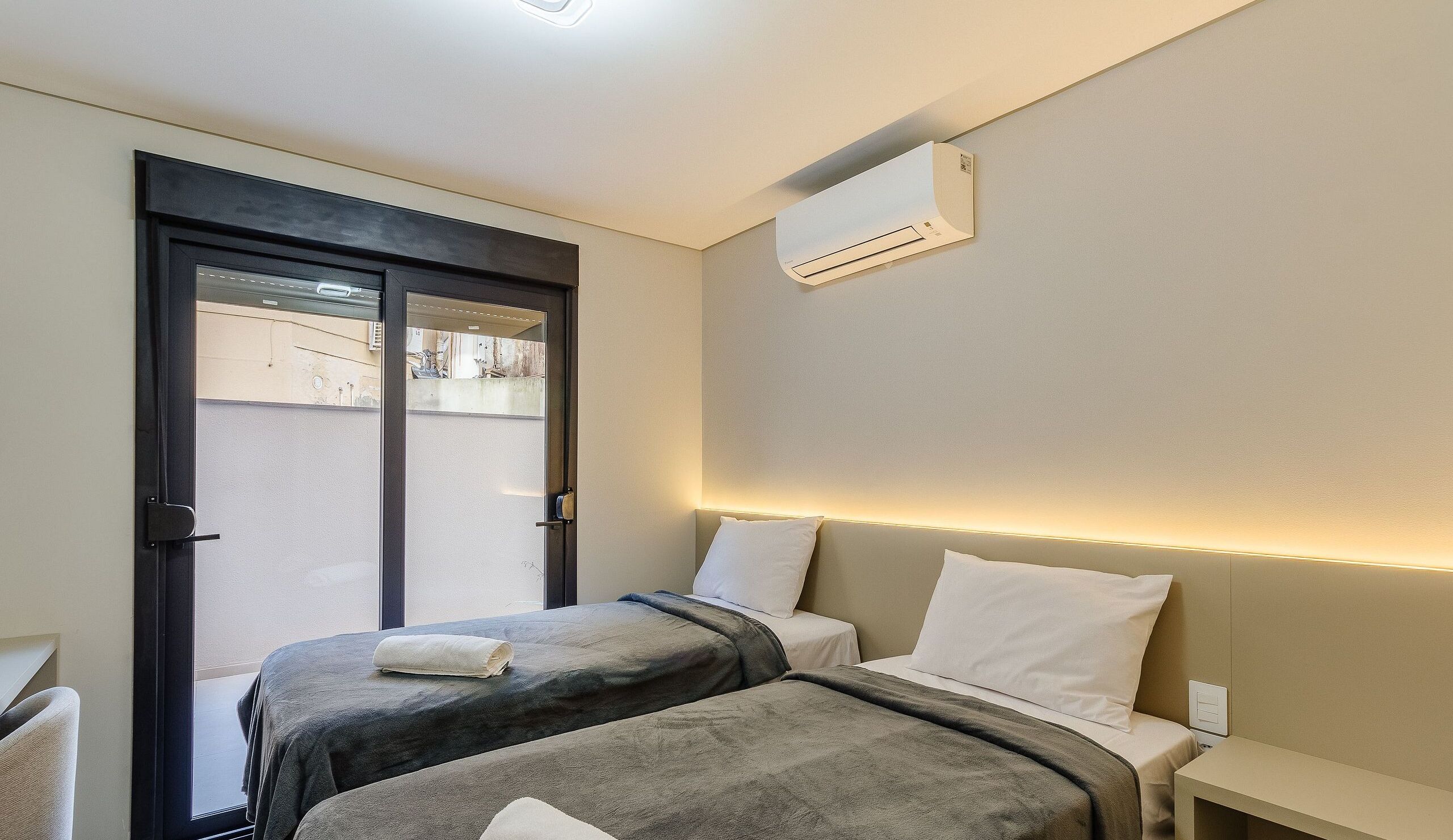 Ein Hotelzimmer mit zwei Betten, einer Tür und einer Klimaanlage.