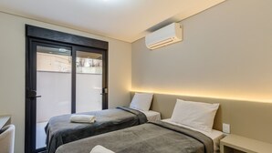 A hotel room with two beds, a door, and an air conditioning unit. - DLH Aptos no Coração de Gramado (Gramado)