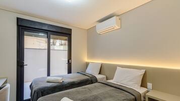 Ein Hotelzimmer mit zwei Betten, einer Tür und einer Klimaanlage.