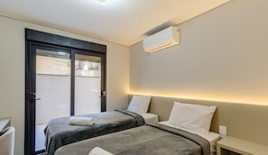 A hotel room with two beds, a door, and an air conditioning unit. - DLH Aptos no Coração de Gramado (Gramado)