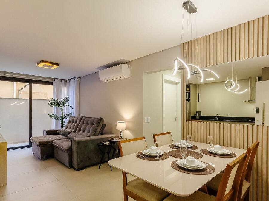 Una sala de estar moderna con un sofá, una mesa de comedor para cuatro personas y una cocina equipada con refrigerador y estufa.