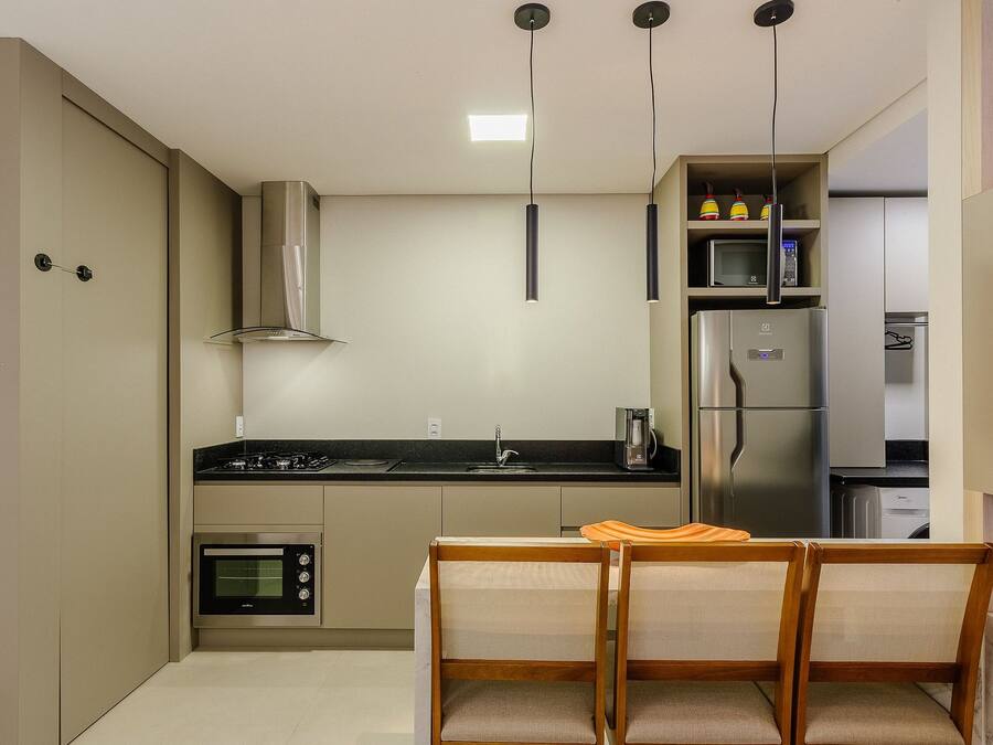 A compact kitchen with a built-in oven, microwave, and refrigerator. There is a dining table with two chairs.