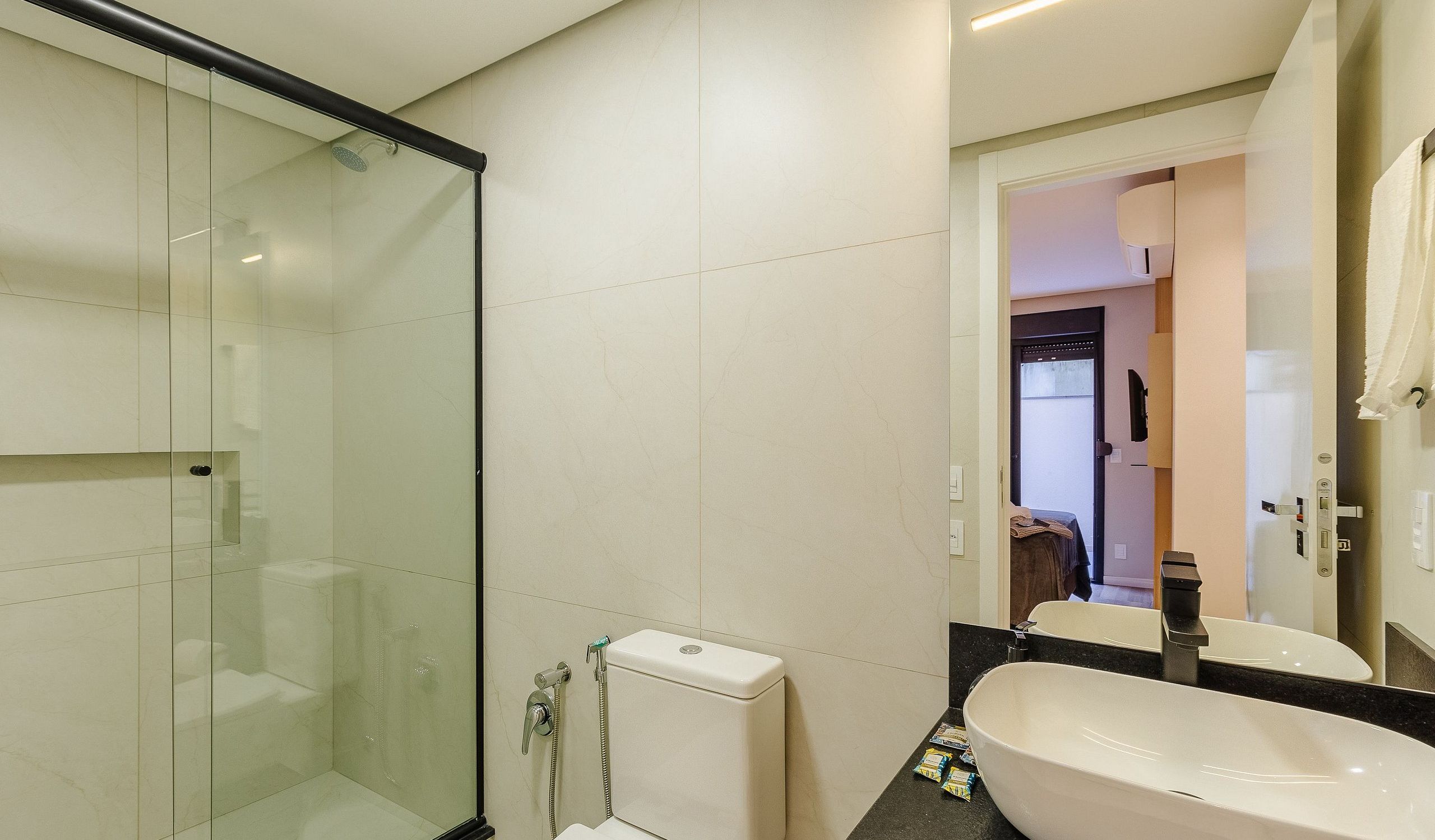 A modern bathroom with a glass shower enclosure, a toilet, and a sink with a mirror.