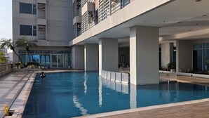 An indoor swimming pool with a wooden deck, large windows, and a modern building structure. - Triple view Condotel Superior manila bay Downtown /st lukes /steps robinson mall (Manila)