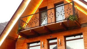 Une cabane en bois dotée d’un balcon, de grandes fenêtres et d’un escalier menant à l’entrée.
