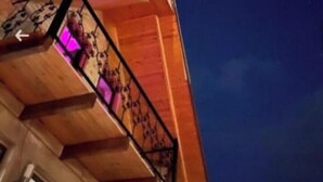 Un bâtiment en bois doté d’un balcon et d’une fenêtre illuminée de lumière violette.