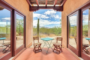 A patio with two wooden chairs and a small table, overlooking a desert landscape with cacti and mountains. - Chic Tucson Casita w/ Deck & Panoramic Views! (Tucson)