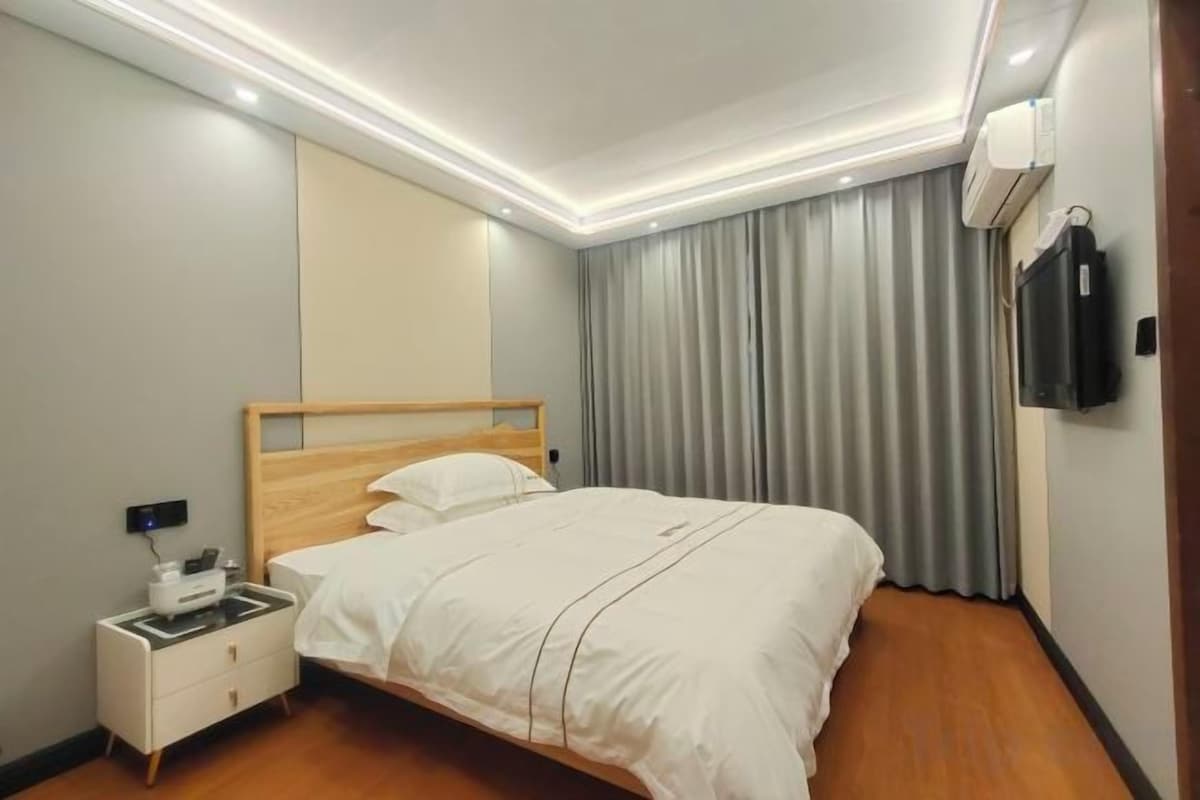 Una camera d'albergo con un letto, un comodino e una TV a parete.