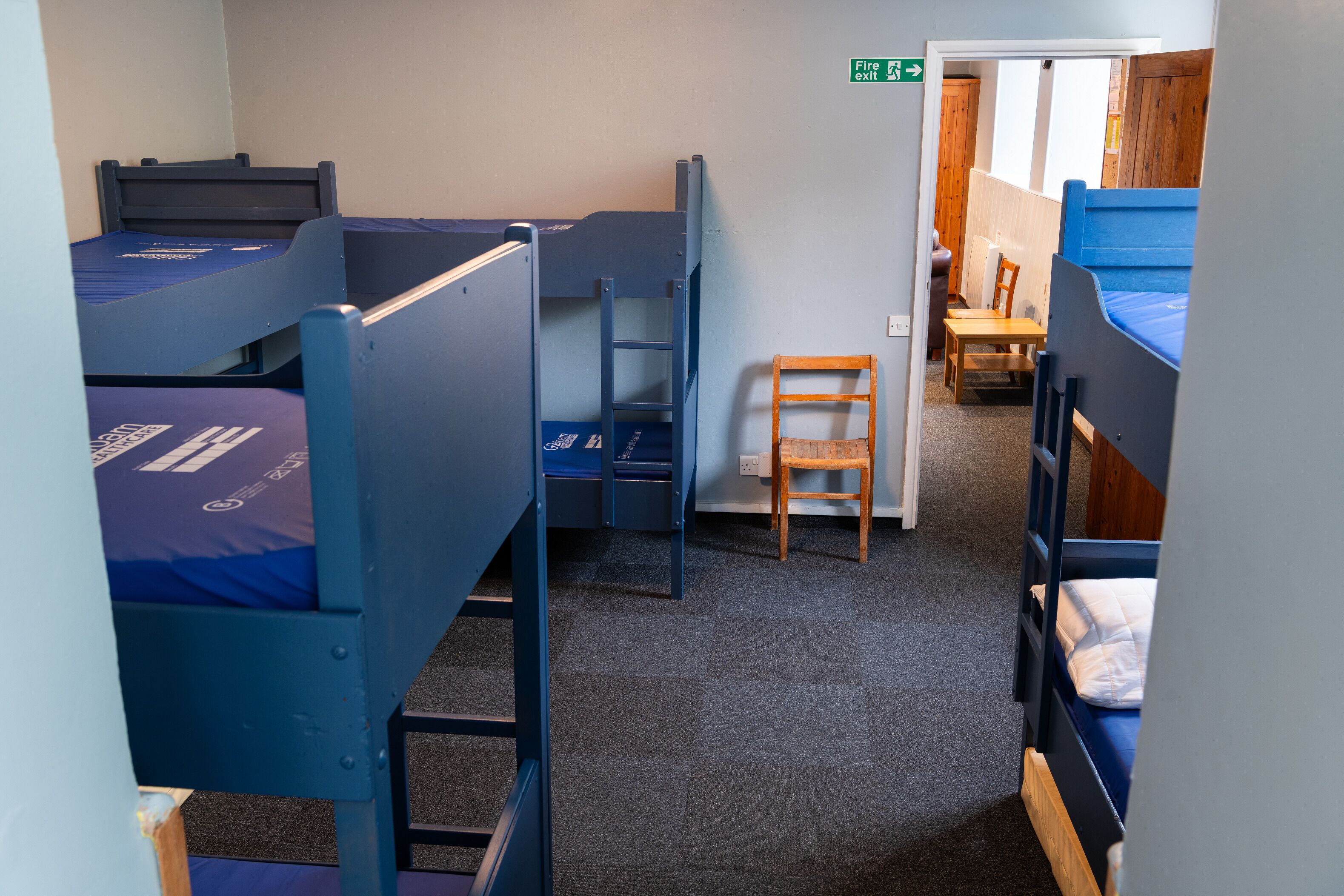 Een slaapzaal met stapelbedden, een bureau en een stoel.