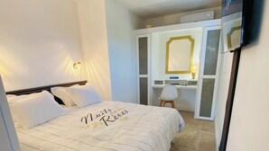 Une chambre à coucher comprenant un lit, un bureau, une chaise, un miroir et un téléviseur.