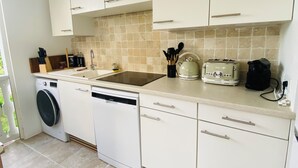Une cuisine compacte avec des meubles blancs, un lave-vaisselle, une machine à laver et un grille-pain.