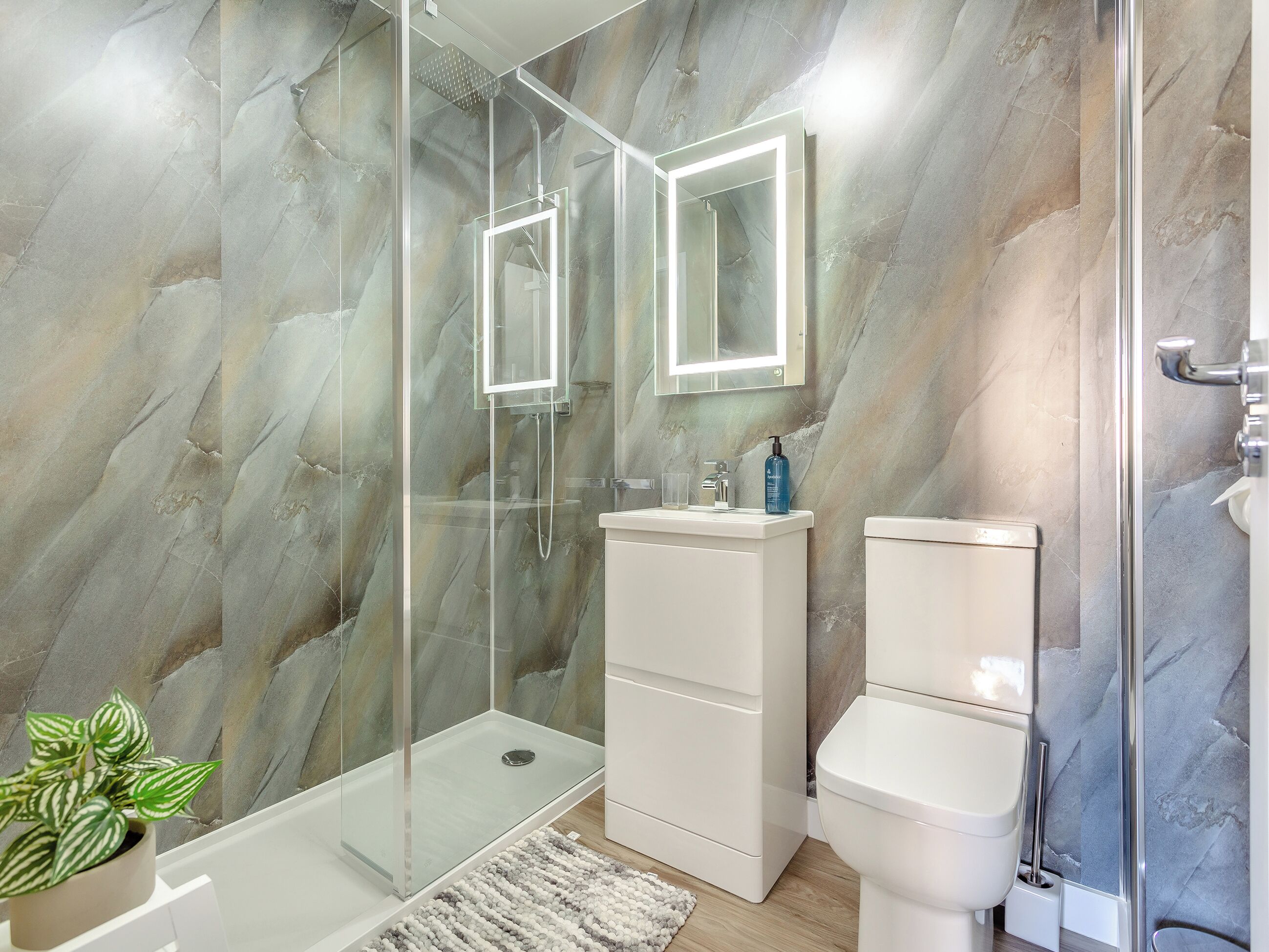 A modern bathroom with a glass-enclosed shower, a white sink, and a toilet.