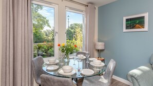 A dining area with a glass table, chairs, and a view of greenery outside. - 2 bedroom accommodation in Nairn (Nairn)