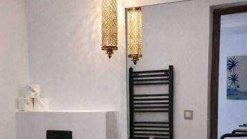 Une salle de bain moderne avec des toilettes noires, un lavabo avec un receveur noir, un porte-serviettes et un luminaire fixé au mur.