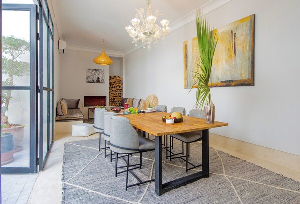 A dining area with a wooden table, grey chairs, and a chandelier. - Riad 48 & Spa (Marrakech)