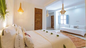 Een ruime slaapkamer met een groot bed, een bank en een decoratieve deur.